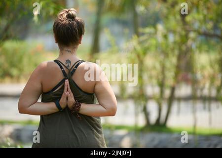 Rückansicht einer jungen, blonden Frau, die auf der Oberseite Yoga beim Sommertag im Freien trägt Stockfoto
