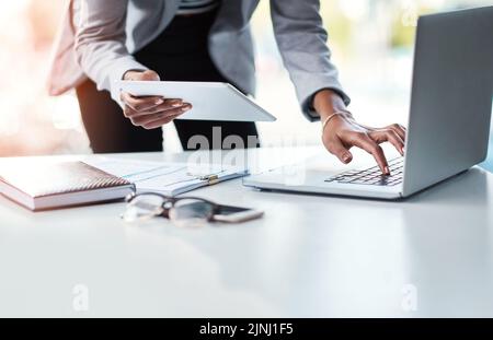 Lesen, Senden oder Prüfen einer E-Mail oder eines Berichts während der Arbeit an einem professionellen Schreibtisch. Hände tippen auf einer Laptop-Tastatur und halten ein Tablet mit einem Stockfoto