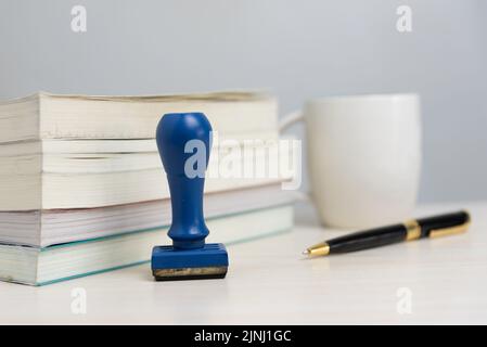 Buch und Gummistempel und Stift auf dem Schreibtisch im Büro Business Concept. Stockfoto