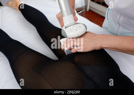 Die Frau erhält eine Flüssiggasmassage, um Cellulite aus ihrem Körper zu entfernen und die Beine zu heben. Konzept-Beauty-Therapie im Spa-Salon. Stockfoto