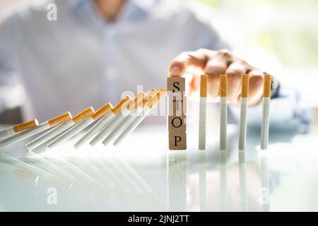 Mann, Der Mit Holzklötzen Die Zigarette Vom Absturz Auf Den Schreibtisch Abhält Stockfoto