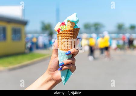 Geschmolzenes Eis vom heißen Sommerwetter in der Hand einer Frau auf dem Hintergrund einer Stadtstraße Stockfoto