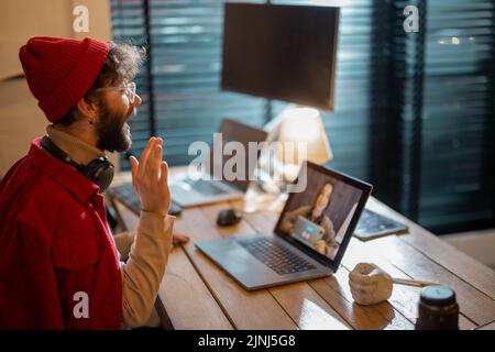 Mann, der sich online mit einer Kollegin trifft, während er zu Hause arbeitet Stockfoto