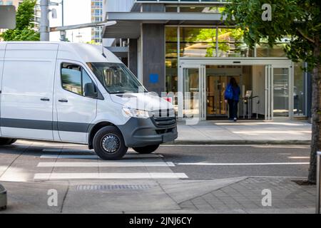 Industriestandard für lokale Lieferungen und Kurzstreckenfrachten oder Dienstleistungen für kleine Unternehmen kompakter, weißer Mini-Van, der zum Parkhaus des Gebäudes wird Stockfoto