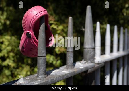 Der rosa Croc-Schuh eines einzelnen Kindes ruht am 10.. August 2022 in London, England, auf einigen Geländern außerhalb des Ruskin Parks. Stockfoto