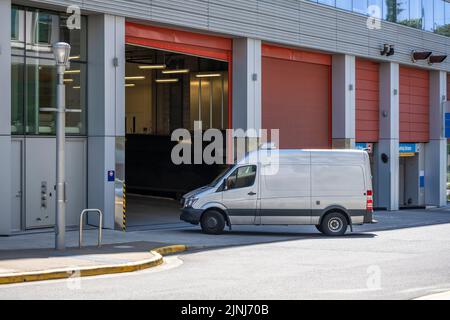 Industriestandard für lokale Lieferungen und Kurzstreckenfrachten oder Dienstleistungen für kleine Unternehmen kompakter, weißer Mini-Van, der zum Parkhaus des Gebäudes wird Stockfoto