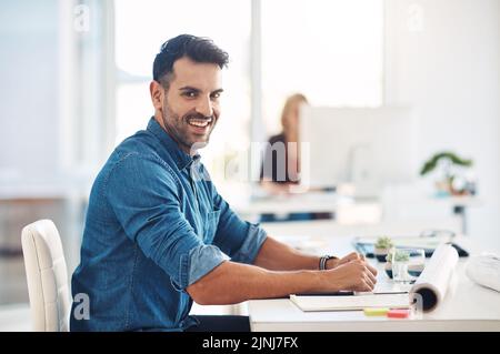 Ein glücklicher, kreativer Geschäftsmann, der an seinem Schreibtisch arbeitet, Verwaltungsaufgaben macht und sich Notizen macht, während er im Büro arbeitet. Porträt eines fröhlichen, lächelnden und Stockfoto