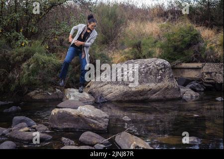 Balancieren auf natürlichen Trittsteinen über einen Fluss im Kamberg Valley in Südafrikas Drakensberg Bergen Stockfoto