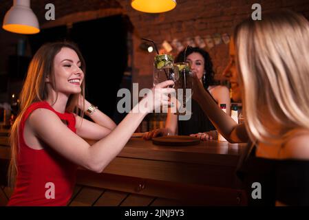 Zwei hübsche kaukasische Mädchen, die im Pub Cocktails trinken und Geburtstag feiern. Stockfoto