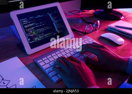 Nahaufnahme eines nicht erkennbaren Programmierers, der während seiner Arbeit spät im Büro notwendige Korrekturen in brandneuer Computeranwendung vornimmt Stockfoto