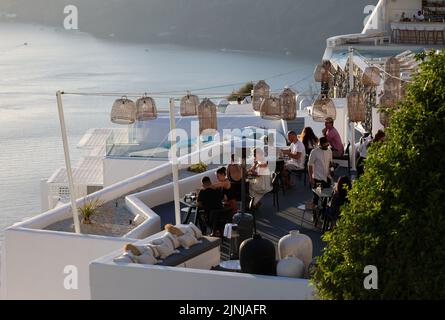 Imergovigli, Santorini, Griechenland - 29. Juni 2021: Tische auf der Restaurantterrasse mit einem malerischen Blick auf den Sonnenuntergang in Imerovigli. Santorini, Greec Stockfoto