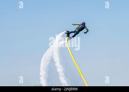 Hydrofyler Jet startet. Junger Mann, der auf dem Wasser auf dem Flyboard Jetski reitet. An Wasserfahrzeuge befestigtes Jetpack-Board mit Hydroflieger. Sommerliche Aktivitäten. Stockfoto