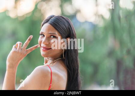 Trans-Frau gestikuliert Sieg mit den Fingern im Freien Stockfoto