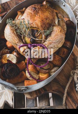 Braten Sie ganzes Hähnchen mit Wurzelgemüse in einer rustikalen Bratpfanne Stockfoto