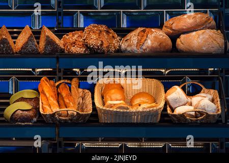 Frisch gebackenes Brot auf Regalen in Bäckerei, Baguette und Brötchen. Verschiedene Arten von leckeren Broten in einem deutschen Bäckerladen. Stockfoto