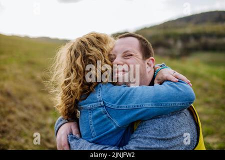 Outdoor-Porträt der Mutter umarmt ihren erwachsenen Sohn mit Down-Syndrom, Mutterschaft Konzept. Stockfoto