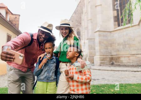 Multirassische Familie, die zusammen mit kleinen Kindern reist. Selfie in der Altstadt. Stockfoto