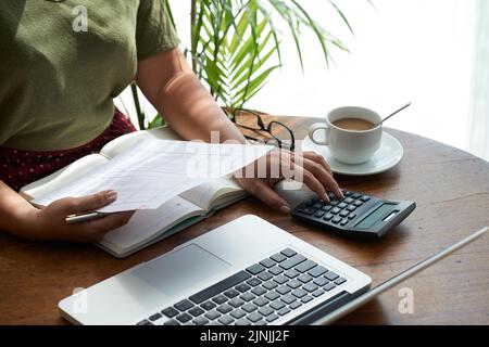 Nahaufnahme eines nicht erkennbaren Finanzmanagers, der am Holztisch sitzt und den Jahresabschluss beendet, Oberfläche mit Sonnenstrahlen beleuchtet Stockfoto