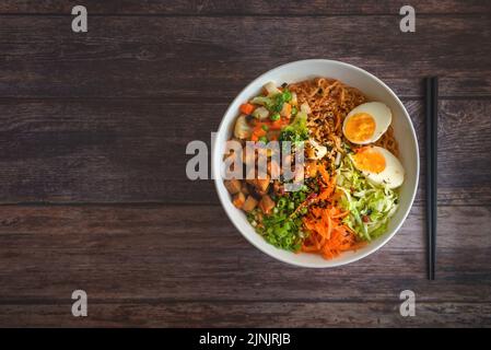 Ein Blick von oben auf die hausgemachte Ramen-Suppe auf einem Holztisch. Stockfoto