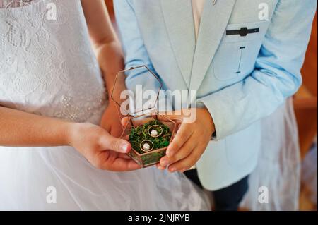 Kinder Hände halten Eheringe in der Box bei der Kirchenfeier. Stockfoto