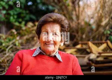 90-jährige ältere Frau im Garten und lacht freudig. Stockfoto