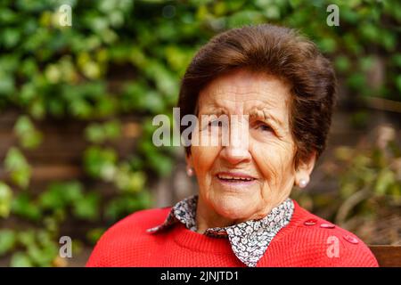90-jährige ältere Frau im Garten und lacht freudig. Stockfoto