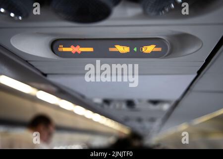 Die Verbotsschilder im Flugzeug zeigen eine gekreuzte Zigarette und eine Empfehlung, sich anzuschnallen Stockfoto