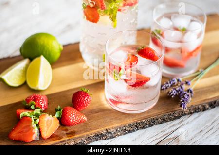 Frisches Getränk mit Erdbeere und Limette auf Holztisch. Gläser mit Limonade und Eis. Sommergetränk. Stockfoto