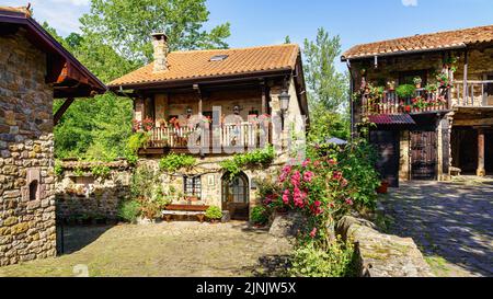 Malerische Steinhäuser im Bergdorf mit Pflanzen und Blumen. Bürgermeister von Barcena. Stockfoto