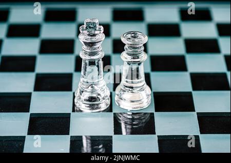 König und Königin auf dem Schachbrett, Makrobild von Glasstücken. Flacher freiheitsgrad, selektiver Fokus Stockfoto