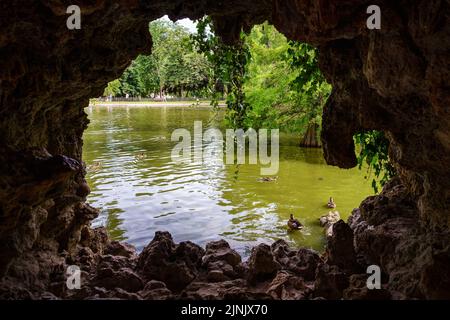 Blick auf den See mit Enten und Vegetation aus einer Felsenhöhle. Das Retiro Madrid. Stockfoto
