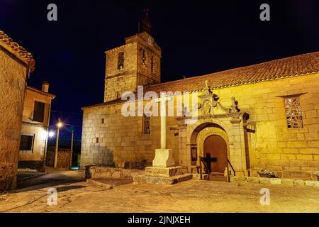 Romanische Kirche bei Nacht mit Glockenturm und Steinkreuz. Stockfoto