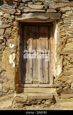 Alte Holztür in mittelalterlichem Steinhaus. Stockfoto