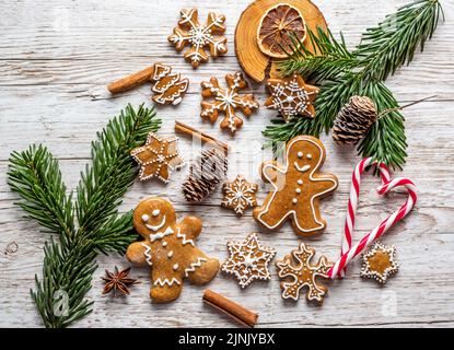 Auf dem Holztisch werden Weihnachts-Lebkuchen und Süßigkeiten gestellt. Kekse und süße Speisen in Form von Sternen und Schneeflocken. Winterthema, rustikaler Stil. Kiefer Stockfoto