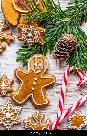 Auf dem Holztisch werden Weihnachts-Lebkuchen und Süßigkeiten gestellt. Kekse und süße Speisen in Form von Sternen und Schneeflocken. Winterthema, rustikaler Stil. Kiefer Stockfoto