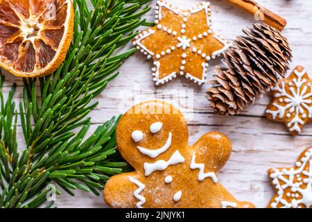 Auf dem Holztisch werden Weihnachts-Lebkuchen und Süßigkeiten gestellt. Kekse und süße Speisen in Form von Sternen und Schneeflocken. Winterthema, rustikaler Stil. Kiefer Stockfoto