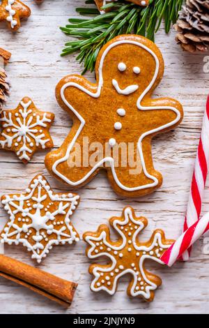 Auf dem Holztisch werden Weihnachts-Lebkuchen und Süßigkeiten gestellt. Kekse und süße Speisen in Form von Sternen und Schneeflocken. Winterthema, rustikaler Stil. Kiefer Stockfoto