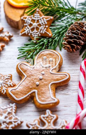 Auf dem Holztisch werden Weihnachts-Lebkuchen und Süßigkeiten gestellt. Kekse und süße Speisen in Form von Sternen und Schneeflocken. Winterthema, rustikaler Stil. Kiefer Stockfoto