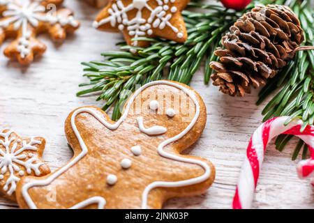 Auf dem Holztisch werden Weihnachts-Lebkuchen und Süßigkeiten gestellt. Kekse und süße Speisen in Form von Sternen und Schneeflocken. Winterthema, rustikaler Stil. Kiefer Stockfoto