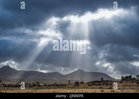 Blick auf Los Ajaches von Puerto del Carmen auf Lanzarote mit Sonnenstrahlen durch die Wolken Stockfoto