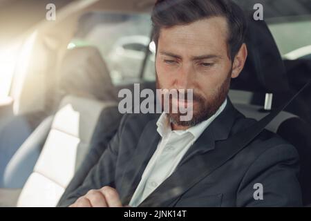 Ein gutaussehender Geschäftsmann in grauem Anzug fährt hinter dem Lenkrad des Autos Stockfoto