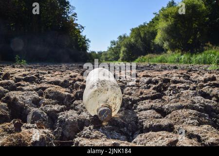 London, England, Großbritannien. 12. August 2022. Eine ausrangierte Plastikflasche liegt in einem vollständig trockenen großen Teich im Wanstead Park im Nordosten Londons, da in Teilen Großbritanniens eine Dürre ausgerufen wird. Anhaltende Hitzewellen infolge des vom Menschen verursachten Klimawandels haben einen Großteil Londons beeinflusst, mit Waldbränden und Dürren in der gesamten Hauptstadt. (Bild: © Vuk Valcic/ZUMA Press Wire) Stockfoto