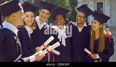 Hochschulabsolventen bei einem Abschlussgespräch, gratulieren sich gegenseitig und besprechen Zukunftspläne. Stockfoto