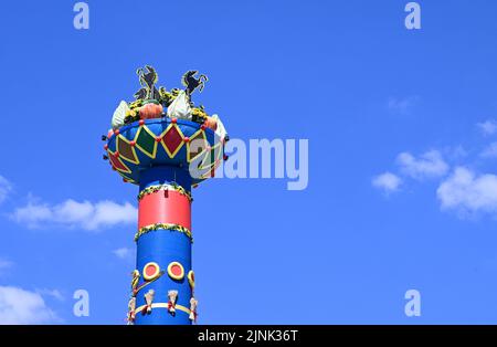 Stuttgart, Deutschland. 12. August 2022. Die Obstsäule, das Wahrzeichen des Cannstatter Wasen Volksfestes, wird nach einer zweijährigen Pause von Corona errichtet. Das Volksfest gilt nach der Münchner Wiesn als das zweitgrößte Festival seiner Art weltweit. Quelle: Bernd Weißbrod/dpa/Alamy Live News Stockfoto