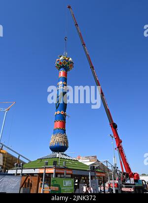 Stuttgart, Deutschland. 12. August 2022. Die Obstsäule, das Wahrzeichen des Cannstatter Wasen Volksfestes, wird nach einer zweijährigen Pause von Corona errichtet. Das Volksfest gilt nach der Münchner Wiesn als das zweitgrößte Festival seiner Art weltweit. Quelle: Bernd Weißbrod/dpa/Alamy Live News Stockfoto