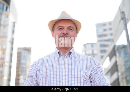 Ethnischer älterer Mann mit Hut, der im Freien läuft Stockfoto