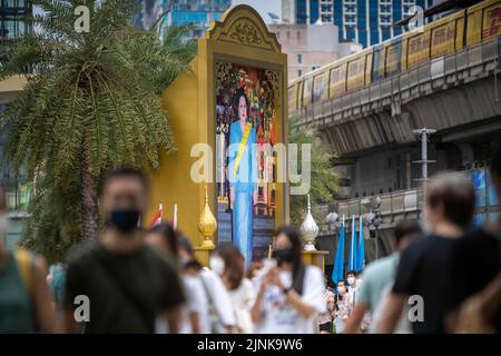 Bangkok, Bangkok, Thailand. 12. August 2022. Vor dem berühmten Einkaufszentrum Siam Paragon in Bangkok kommen die Menschen an einem großen Porträt der Königlichen Hoheit, der Königin Sirikit, vorbei. Die Königin Mutter von Thailand, ihre Königinnen Sirikit, feierte am Freitag, den 12. August 2022, ihren 90.. Geburtstag. Ihr verstorbener Ehemann, HRH, König Bhumibon, regierte über 70 Jahre, der längste aller Könige in der thailändischen Geschichte und der drittlängste der Welt. Die Mutter des heutigen Monarchen, König Vajiralongkorn, die Königin Mutter, litt unter Krankheit und hat in letzter Zeit keine öffentlichen Auftritte gemacht. (Bild: © Adryel Talamantes/ZUMA Stockfoto