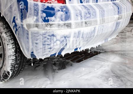 Ein Teil des Wagens in Schaumstoff an der Autowaschanlage aus nächster Nähe Stockfoto