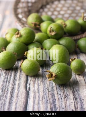 Wilde Guava-Früchte auf einer Holzoberfläche verstreut, frisch geerntete tropische Früchte, die mit Nährstoffen verpackt sind, weicher Hintergrund Stockfoto