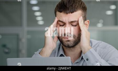 Nahaufnahme müde nachdenkliche Geschäftsmann Blick auf Laptop-Bildschirm leiden unter Überlastung Gefühl Kopfschmerzen schmerzhafte Symptom Migräne Reiben Tempel jung Stockfoto